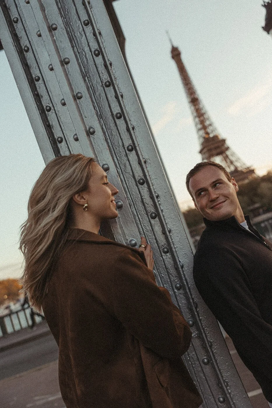 Couple photographed at sunrise in Paris with the Eiffel Tower in soft morning light.