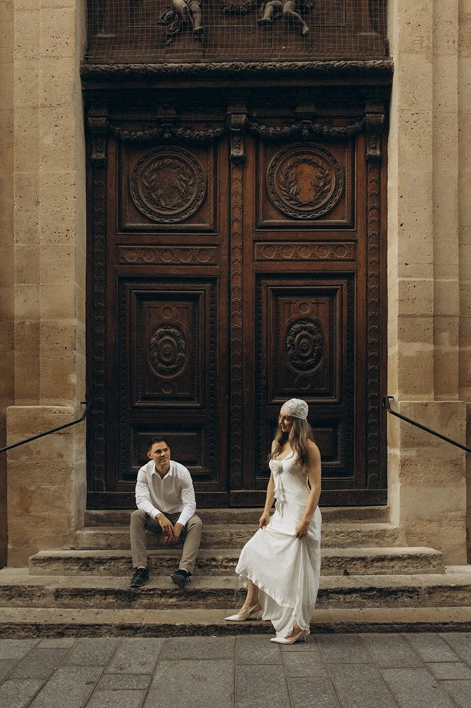 Playful couple sitting on steps in Il Saint Louis during their Paris engagement session, relaxed and authentic love story photography.