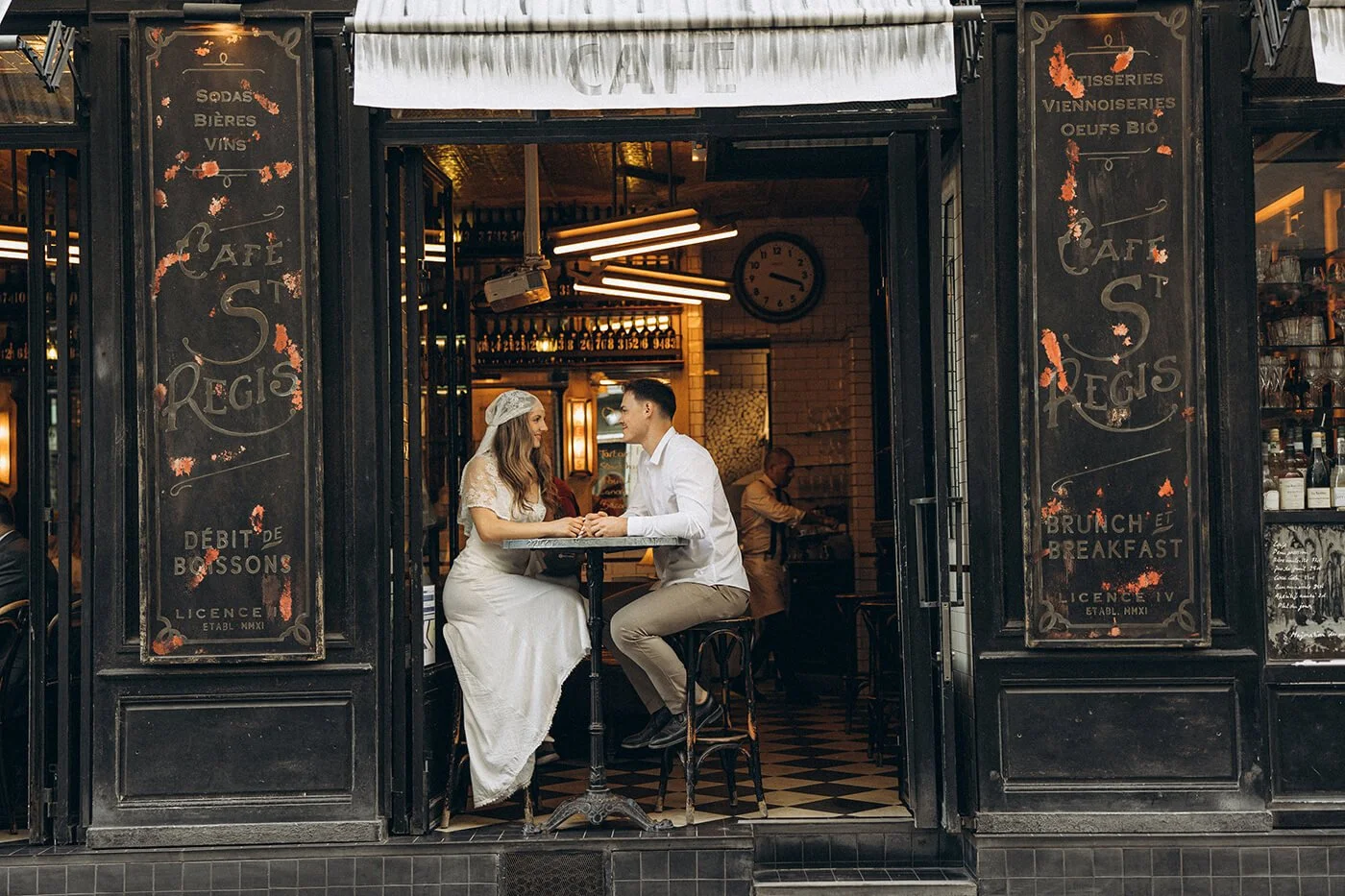 Playful couple sitting in typical Parisian restaurant in Ile Saint Louis during their Paris engagement session, relaxed and authentic love story photography.