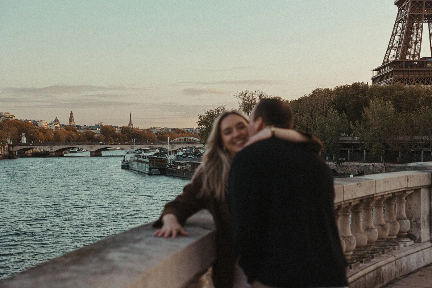 Couple embracing during a candid Paris photoshoot with the Eiffel Tower behind them.