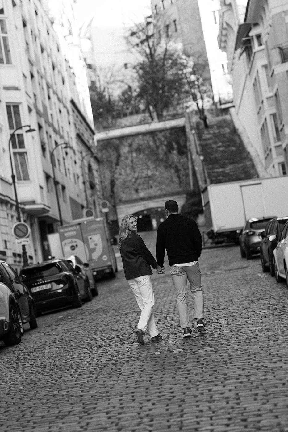 Black and white candid photo of a couple walking through the streets of Paris.