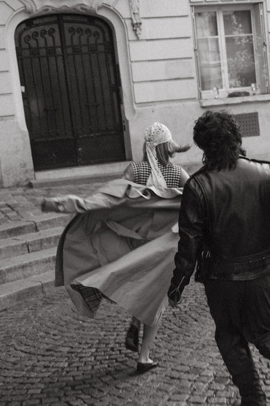 Black and white cinematic portrait of a couple in motion on a Paris street, timeless engagement photography in Montmartre.