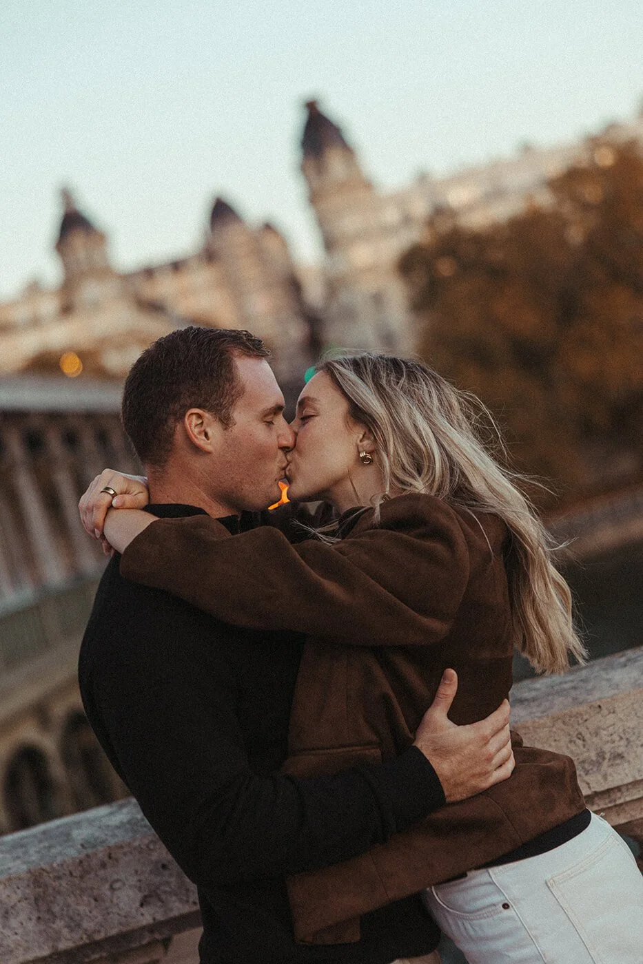 Romantic couple kissing during a sunrise Paris photoshoot by the river.
