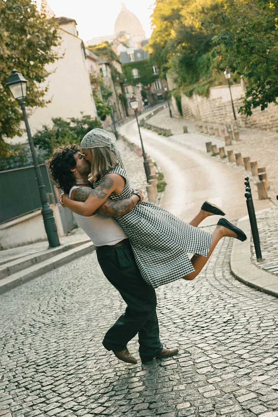 Couple twirling on cobblestone streets in Paris during a romantic engagement session, natural movement captured by a Paris engagement photographer.