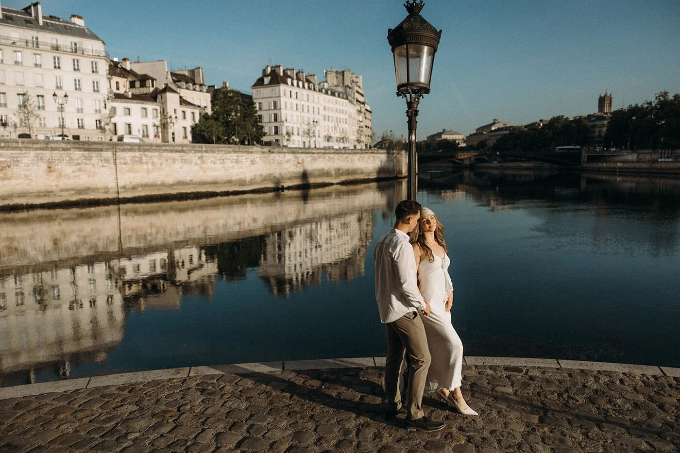 Sunlit portrait of a stylish couple during their engagement session in Paris, cinematic golden light near the Seine River.