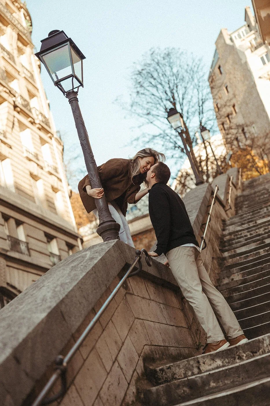 Cinematic couple session in Paris on a stone staircase with elegant city details.