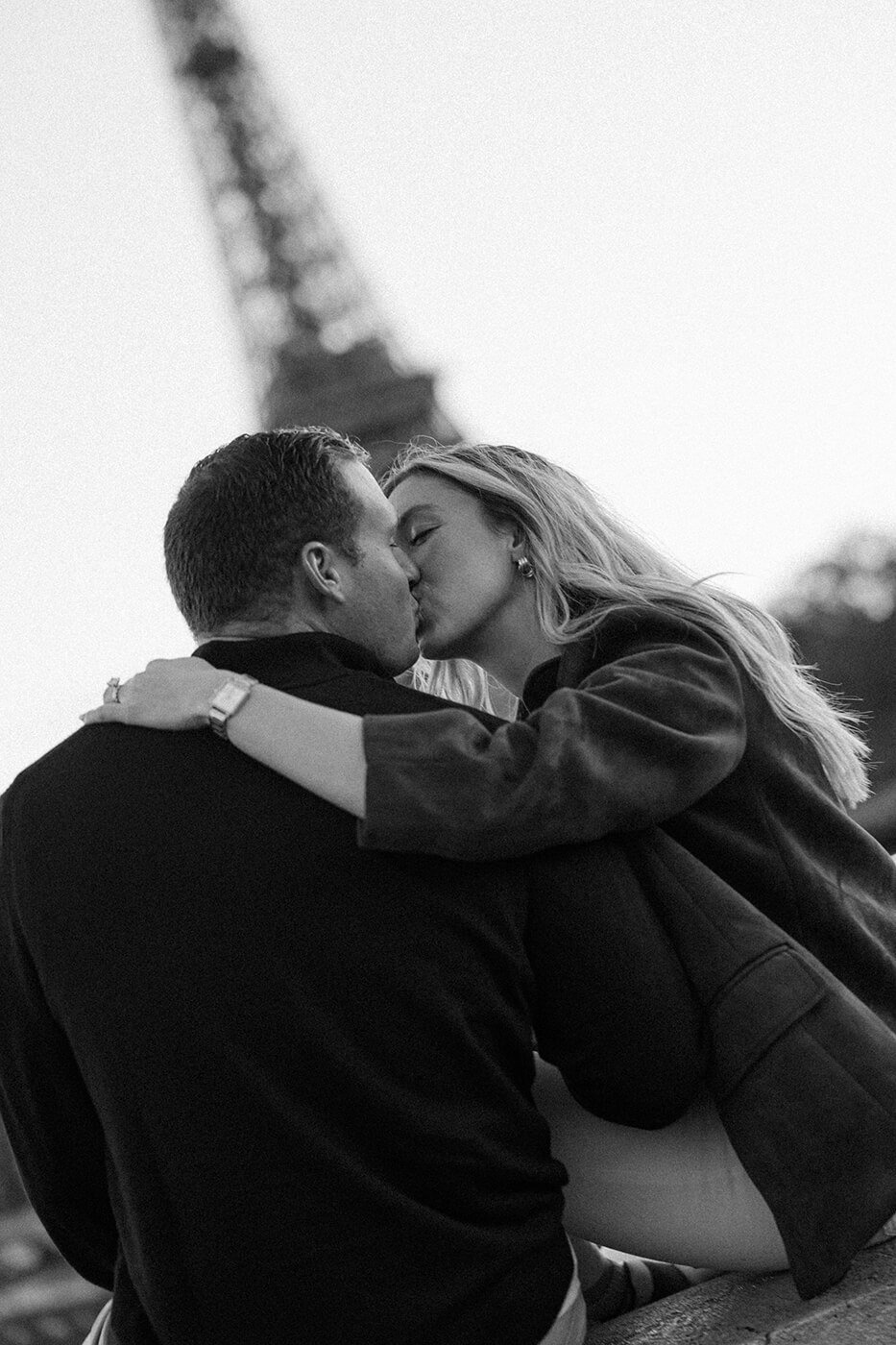 Black and white candid couple kiss during a romantic Paris photoshoot.