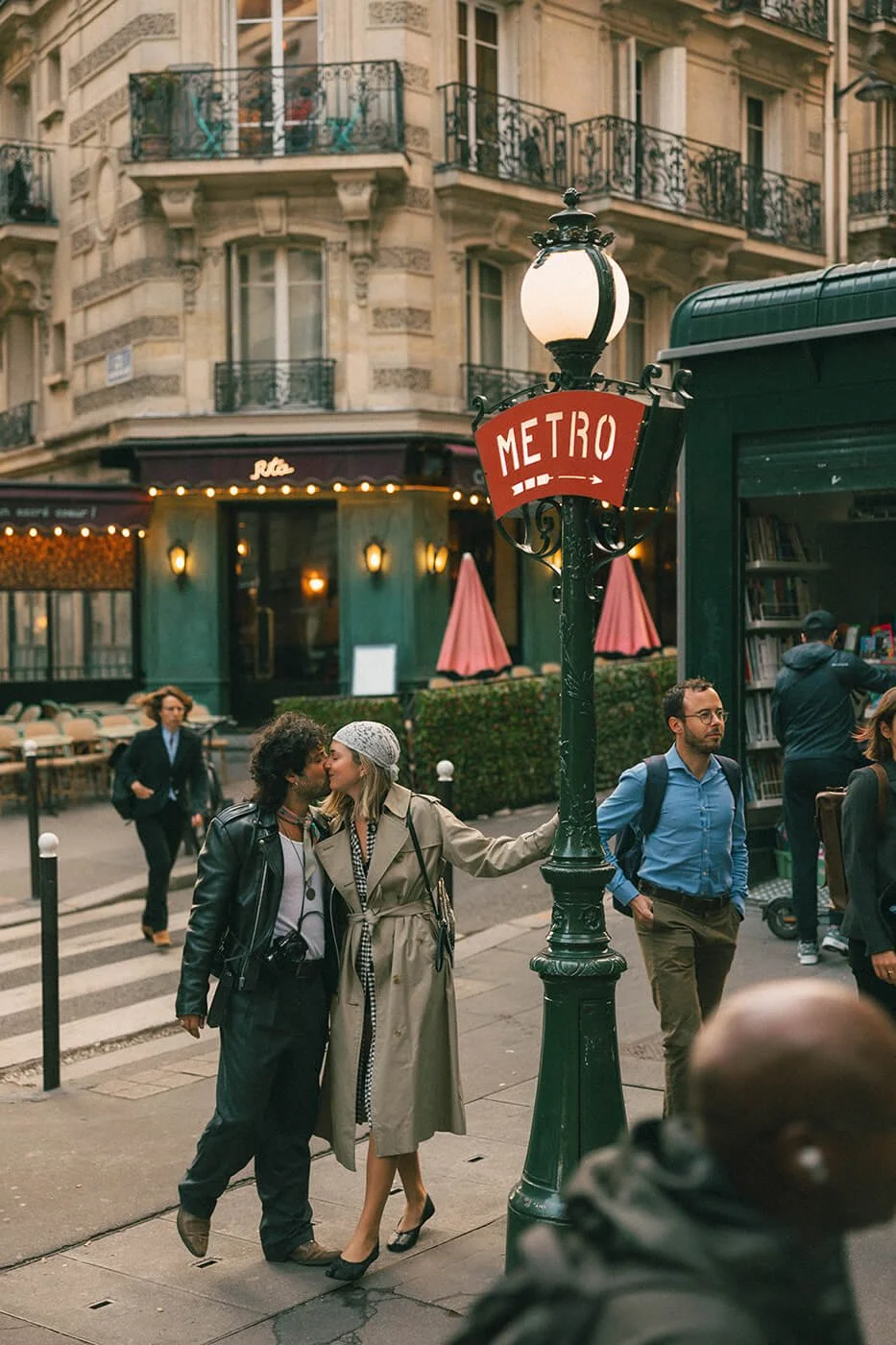 A couple kissing during an engagement photoshoot in Montmartre by a metro sign.