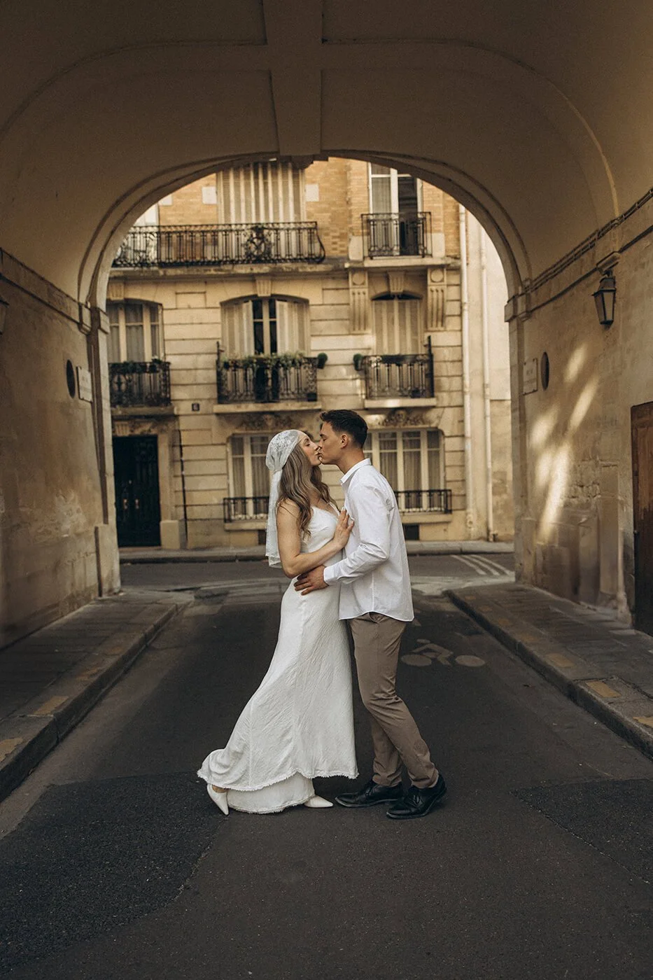 Joyful couple kissing in Paris with historic architecture behind them, candid elopement photography by a Paris elopement photographer.