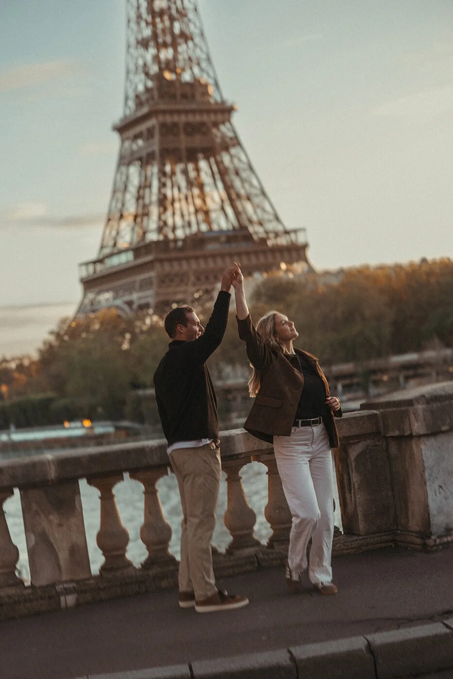 Couple photographed at sunrise in Paris with the Eiffel Tower in soft morning light.