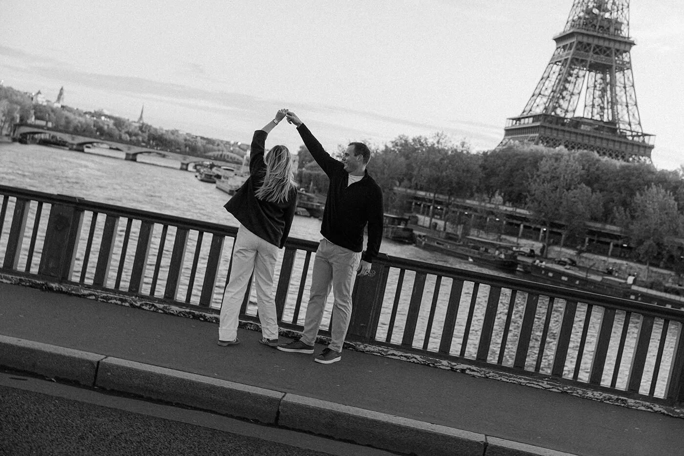 Romantic Paris couple session with the Eiffel Tower visible from a scenic riverside viewpoint.