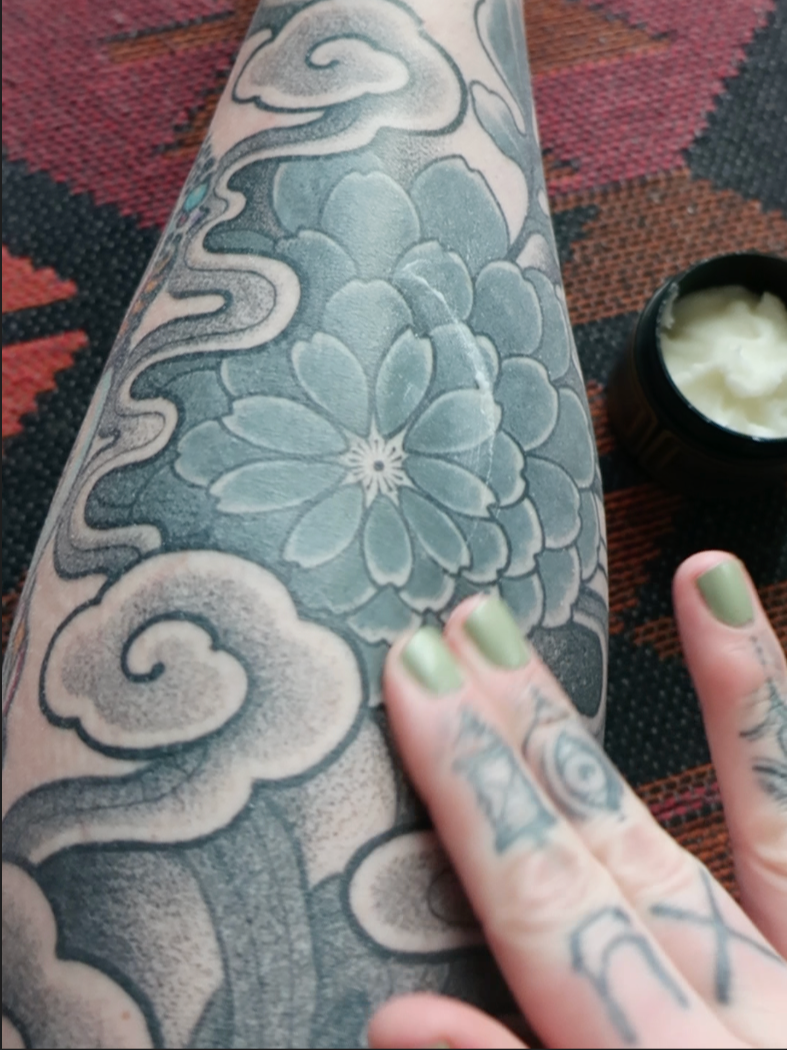 Tattoo client applying aftercare to tattooed skin