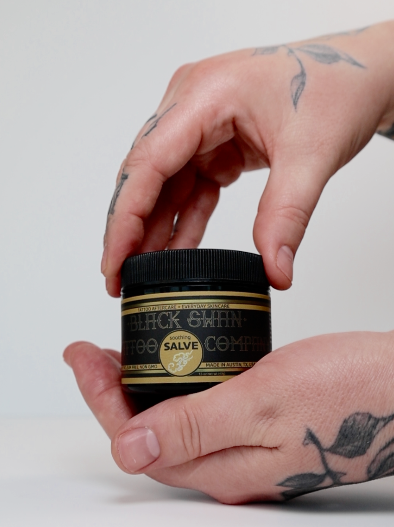Tattooed hands holding tattoo healing soothing salve