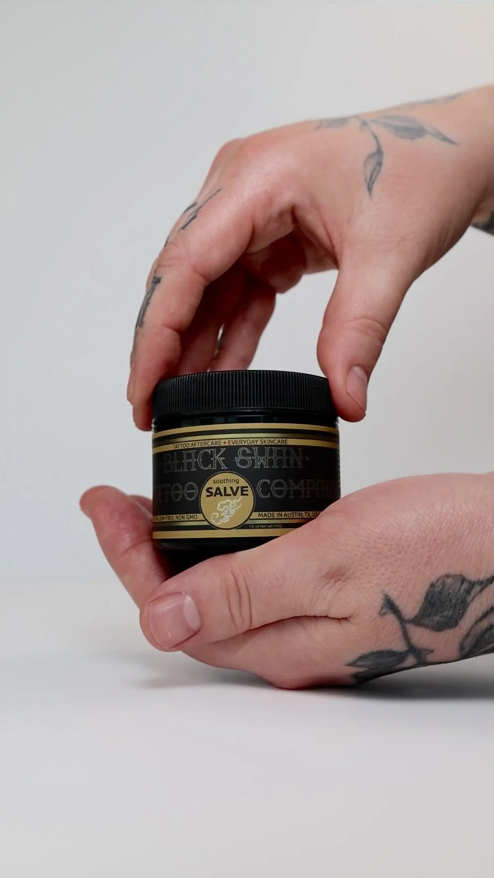 Soothing tattoo salve held in hands minimal clean application style