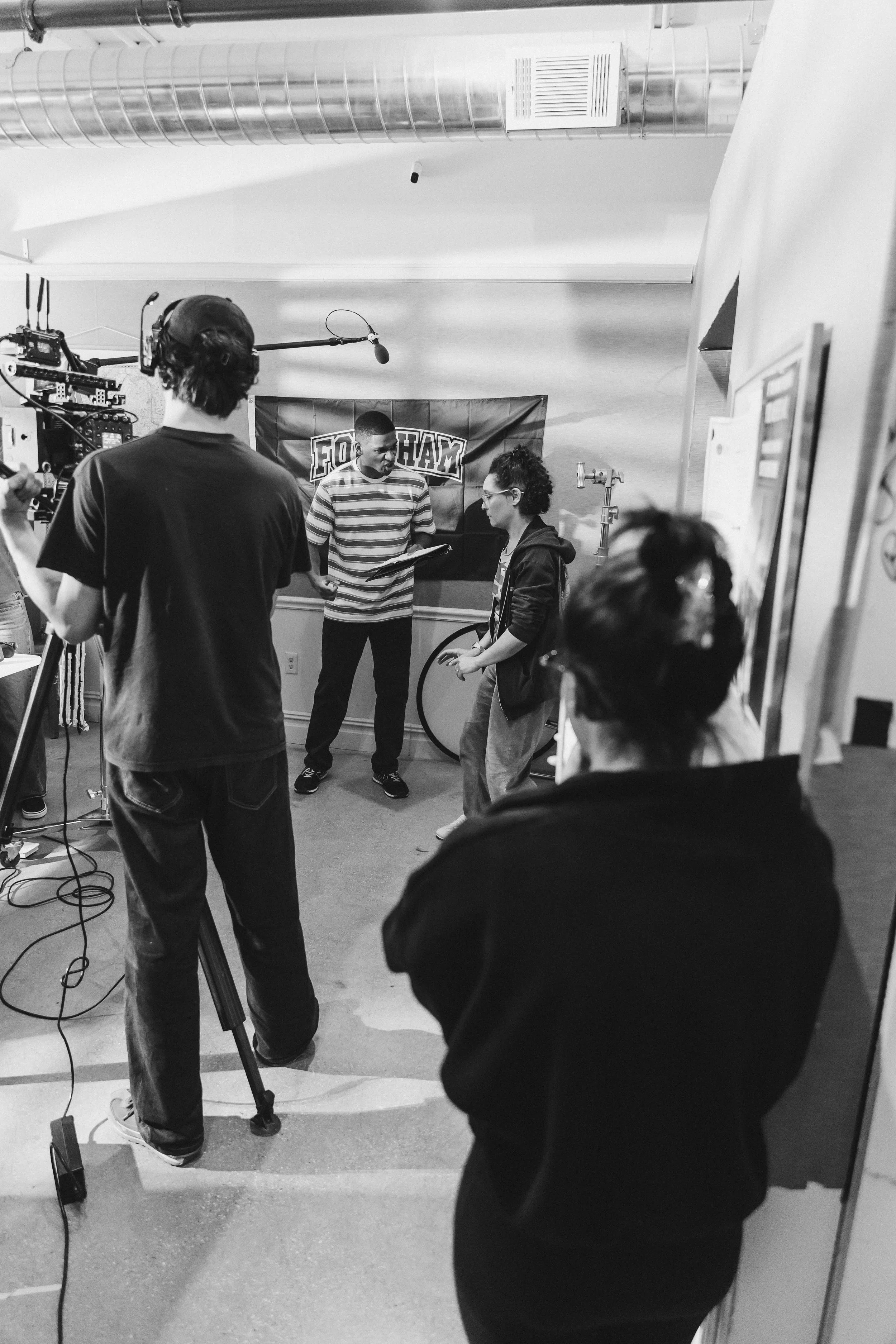 Film crew filming a scene with two actors in a room with a 'Foghorn' banner on the wall.