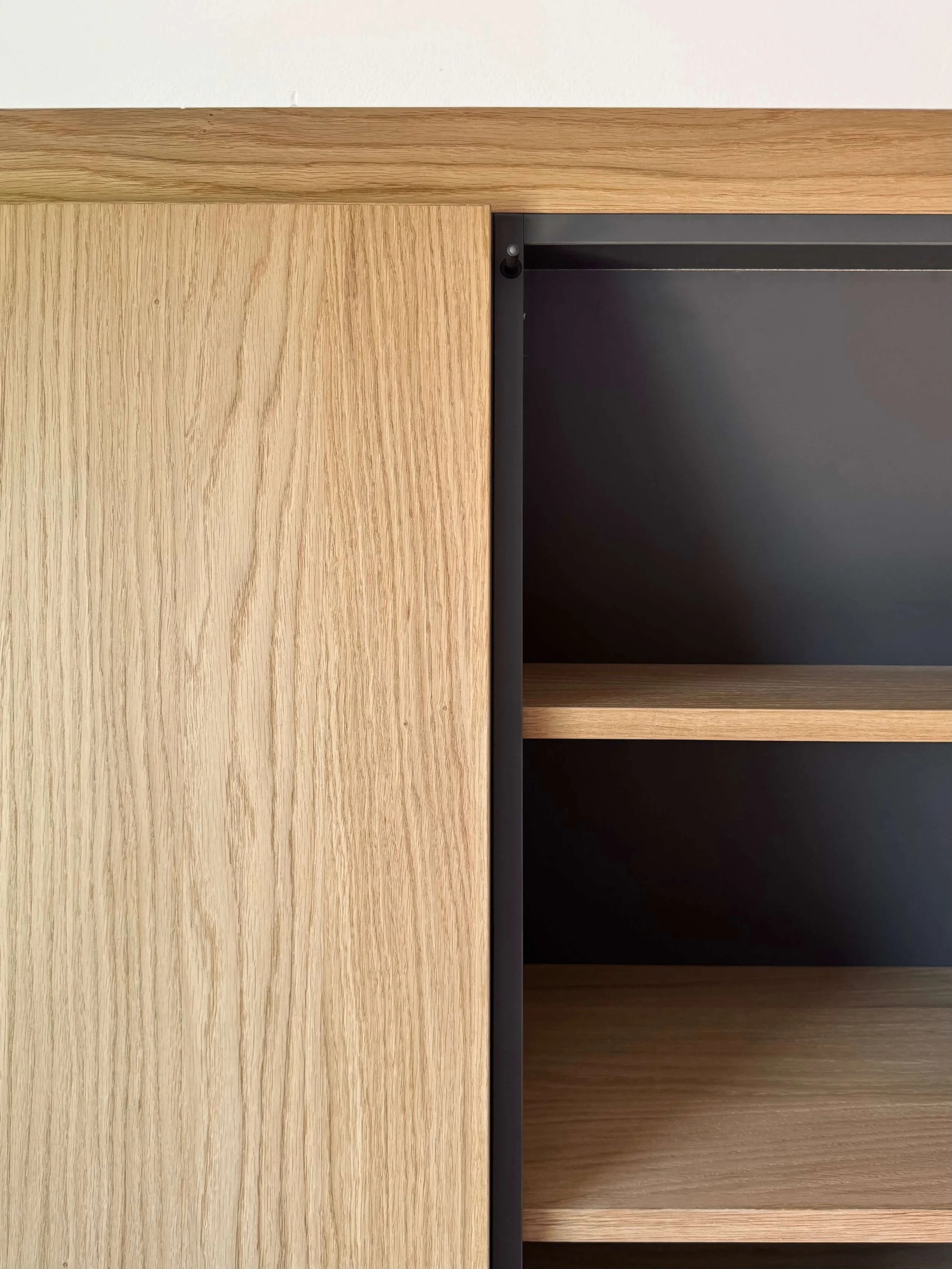 Close-up of a wooden cabinet with black interior shelves.
