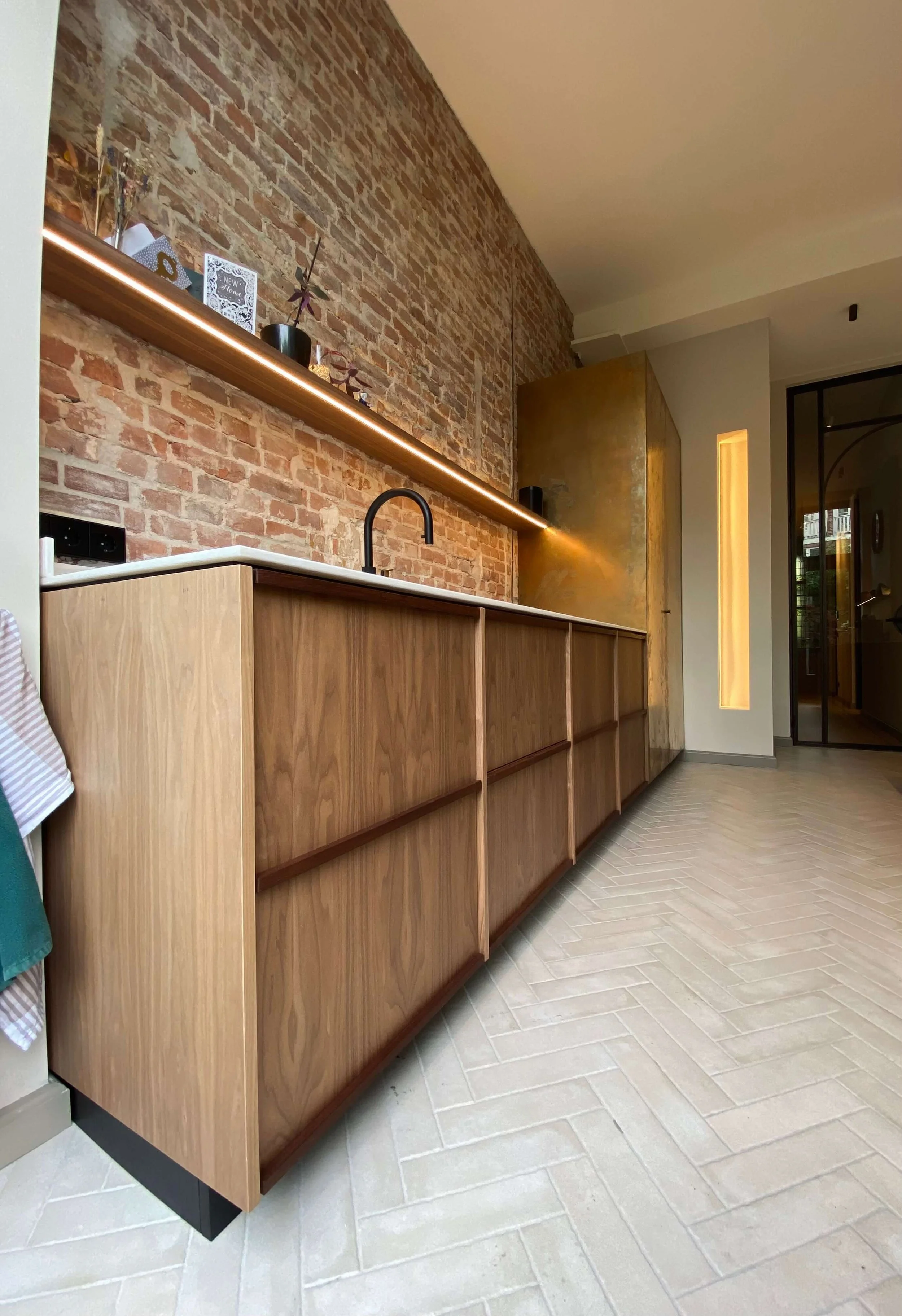 Modern kitchen with wooden cabinets, a brick accent wall, and a black faucet.
