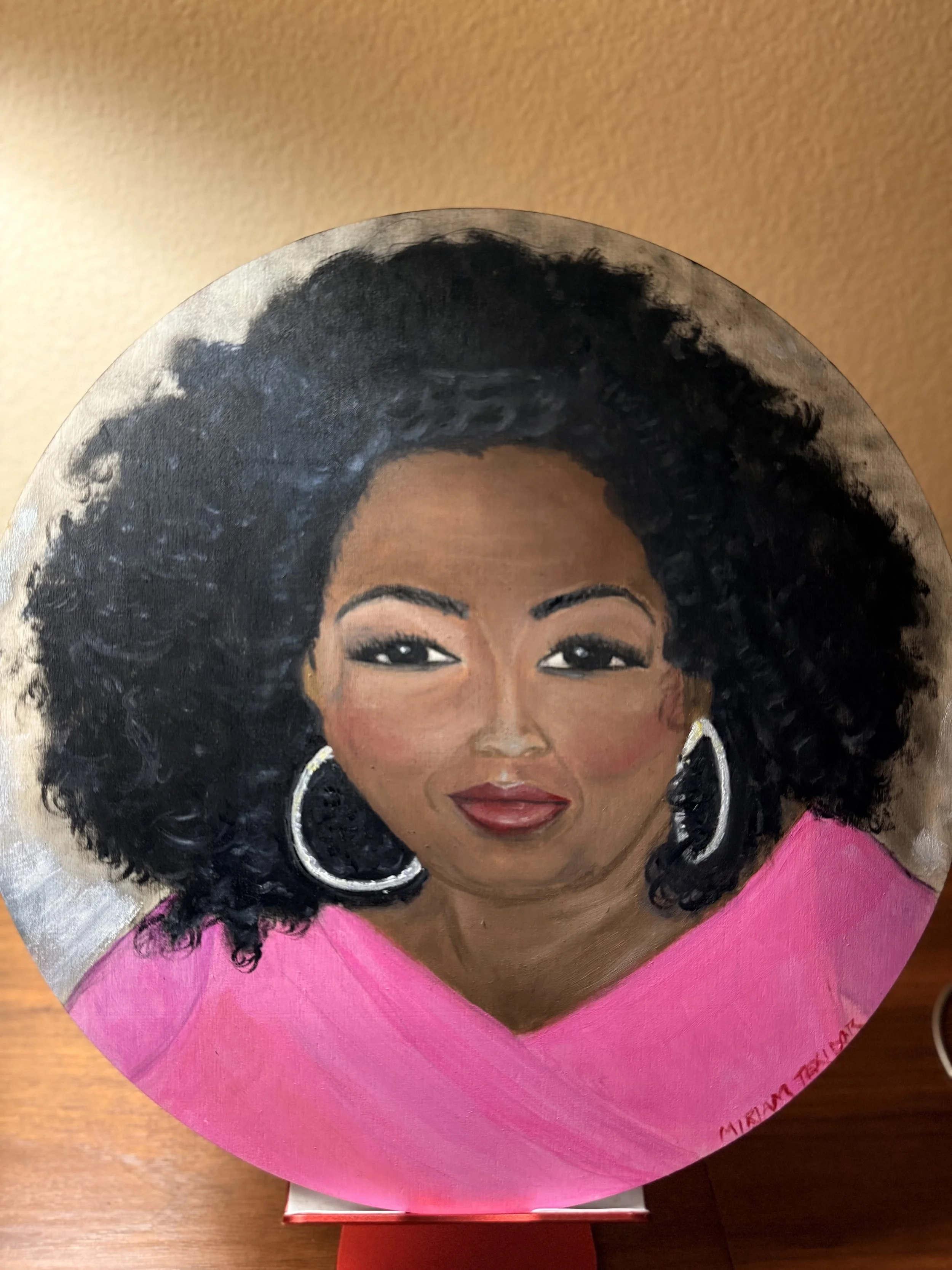 Hand-painted portrait from an online photo of "Oprah Winfrey" by artist Miriam Texidor wearing large hoop earrings and a pink top.