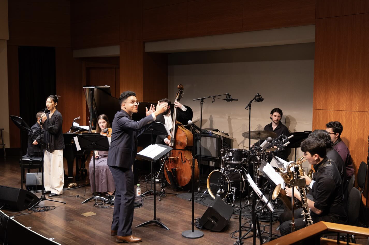 A jazz band performing on stage with singers and musicians playing various instruments, including a piano, double bass, drums, and wind instruments.