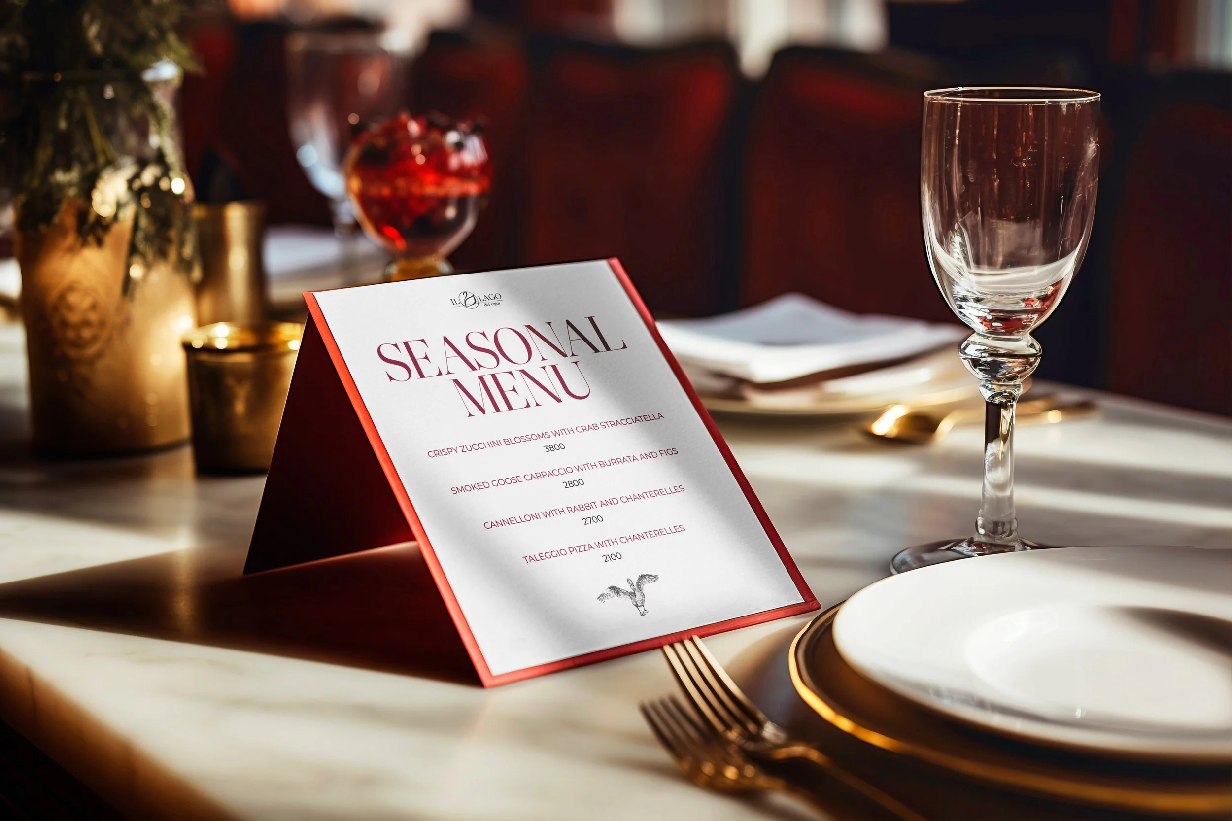 A restaurant table setting with a seasonal menu, wine glass, and plates, with decorative vases and candles in the background.
