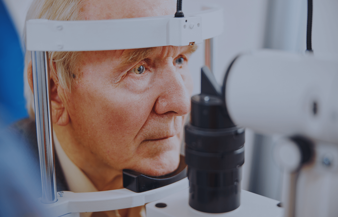 A senior man undergoing an eye exam using a slit lamp microscope.