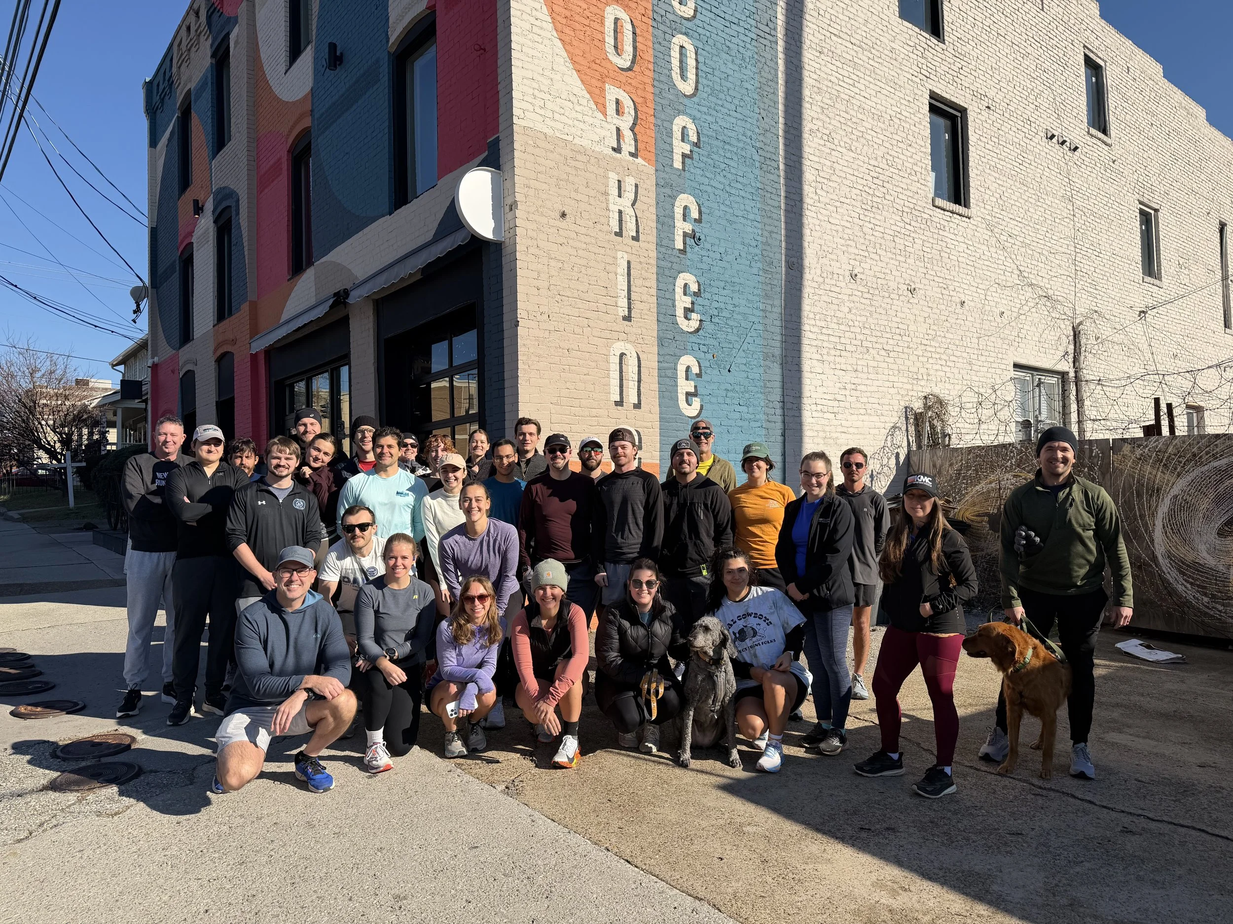 Silhouette of four runners on a track at sunrise or sunset.