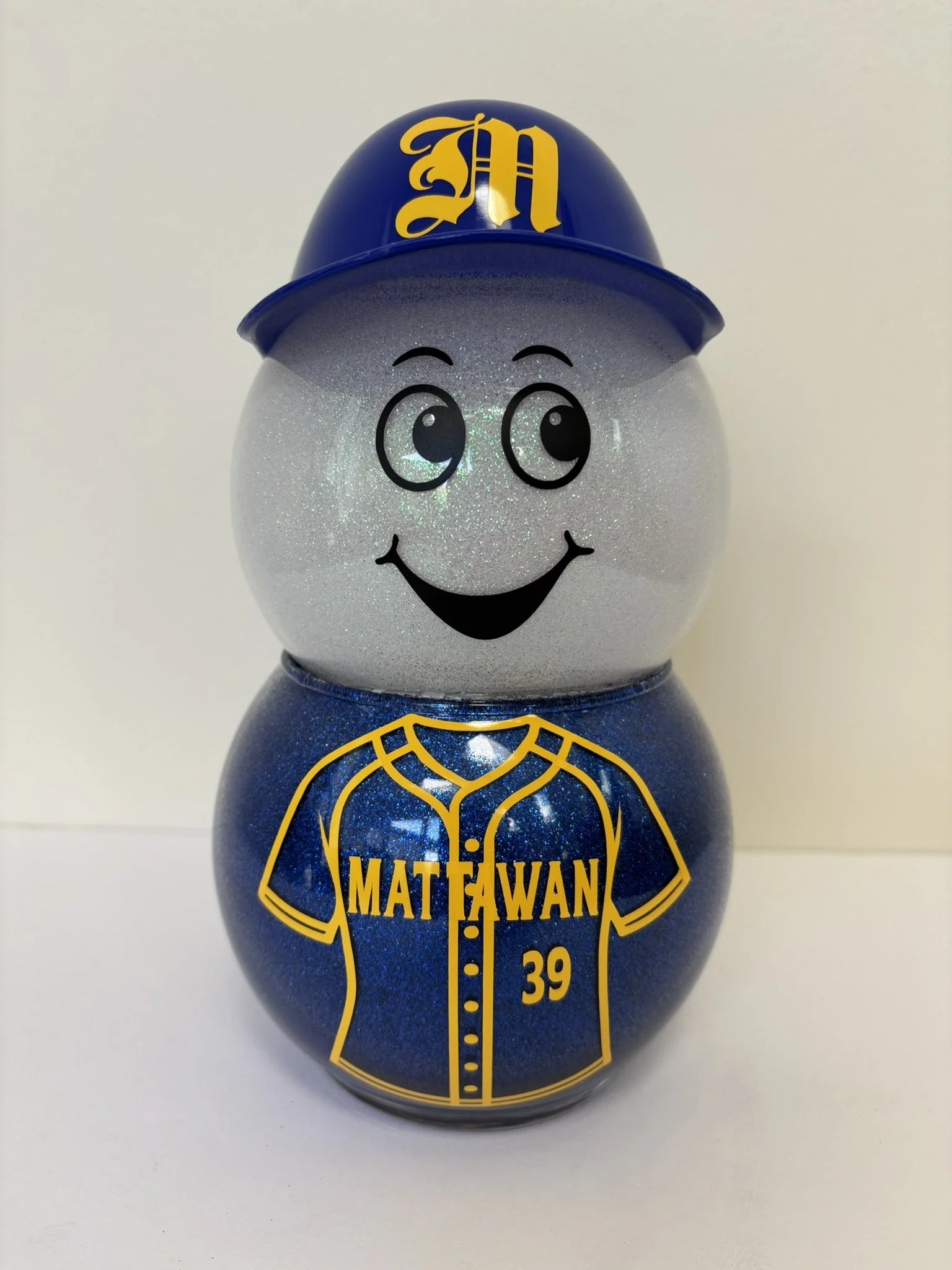 Glass with colored top and bottom.  Blue hat on top with monogram.  Face on top glass.  Jersey with city and number on front and player's name and number on back of the jersey on back of bottom bowl.