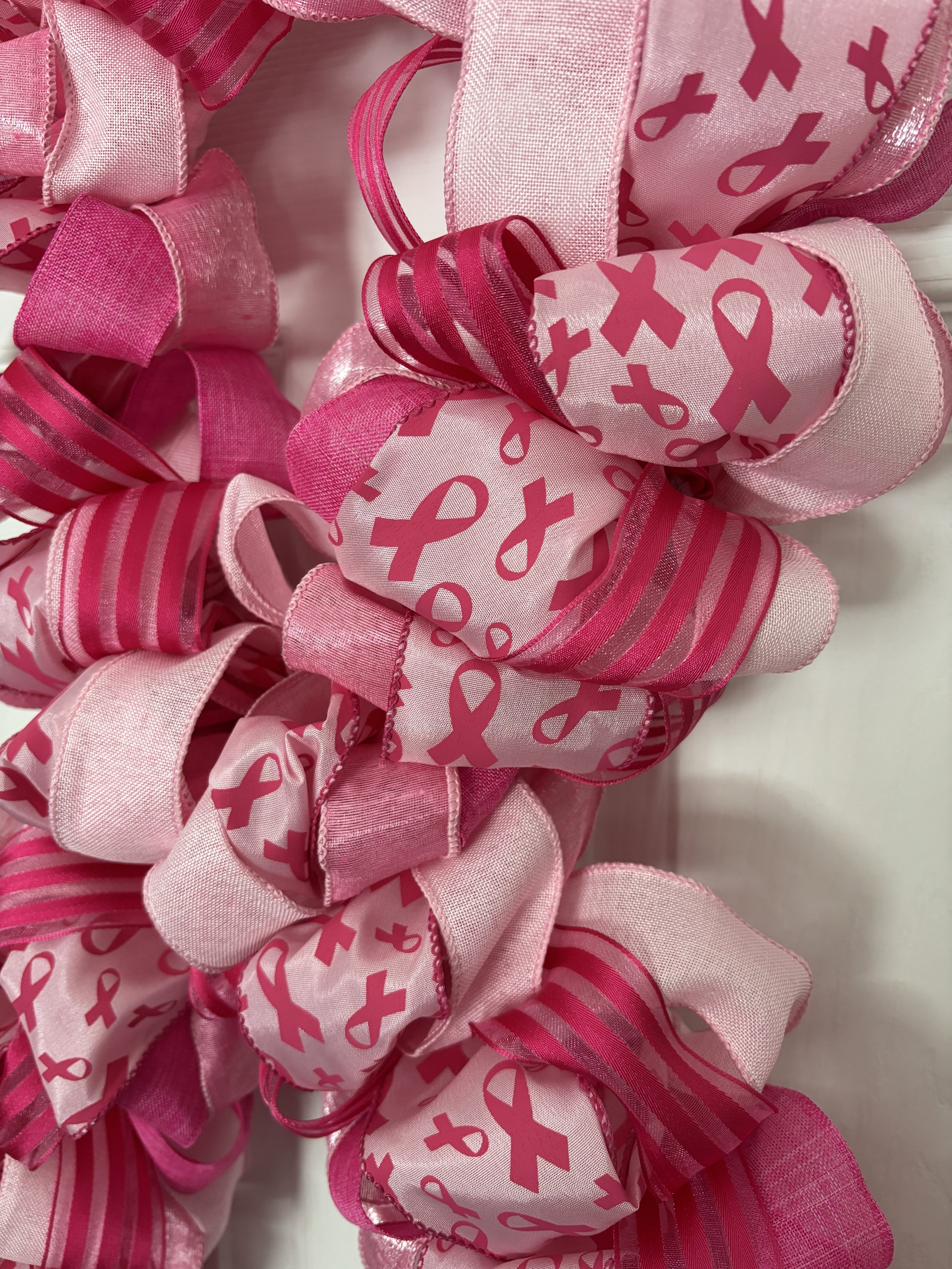 Light and dark pink ribbon with dark pink ribbon shapes on pink ribbon.  Wreath is shaped like a bow to mimic the breast cancer symbol.