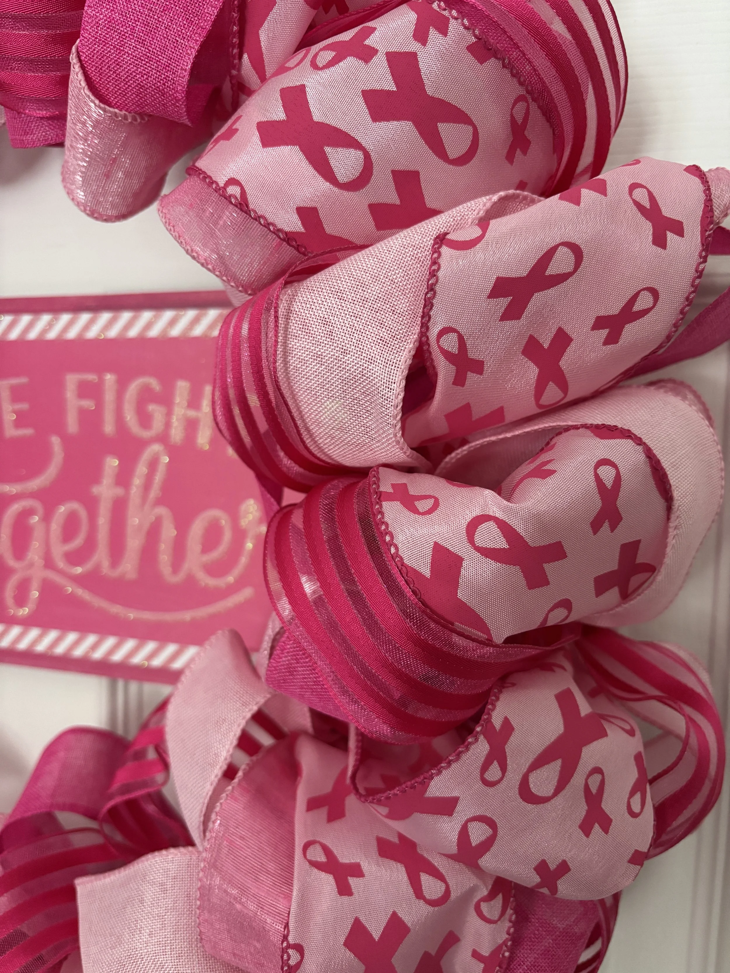 Pink and red ribbon wreath with pink bows signifying breast cancer on the pink ribbon and a pink sign in the middle with gold letters that says We Fight Together and a gold breast cancer ribbon.