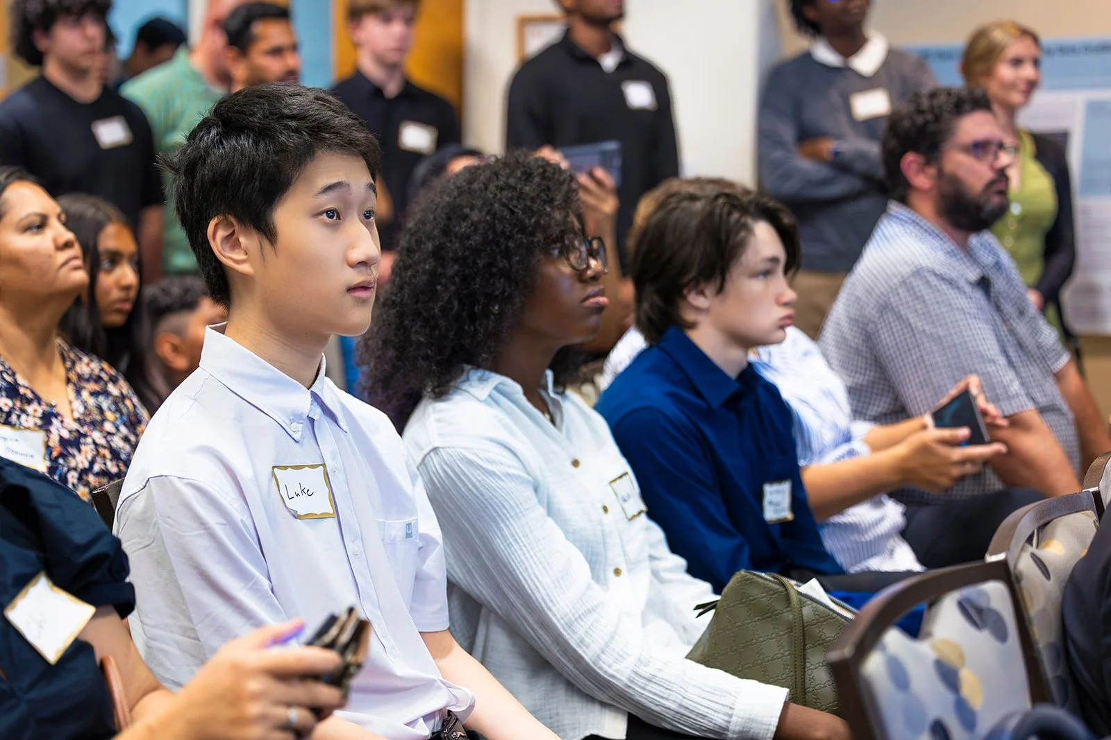Group of diverse people attending an indoor conference or seminar, sitting and listening attentively.