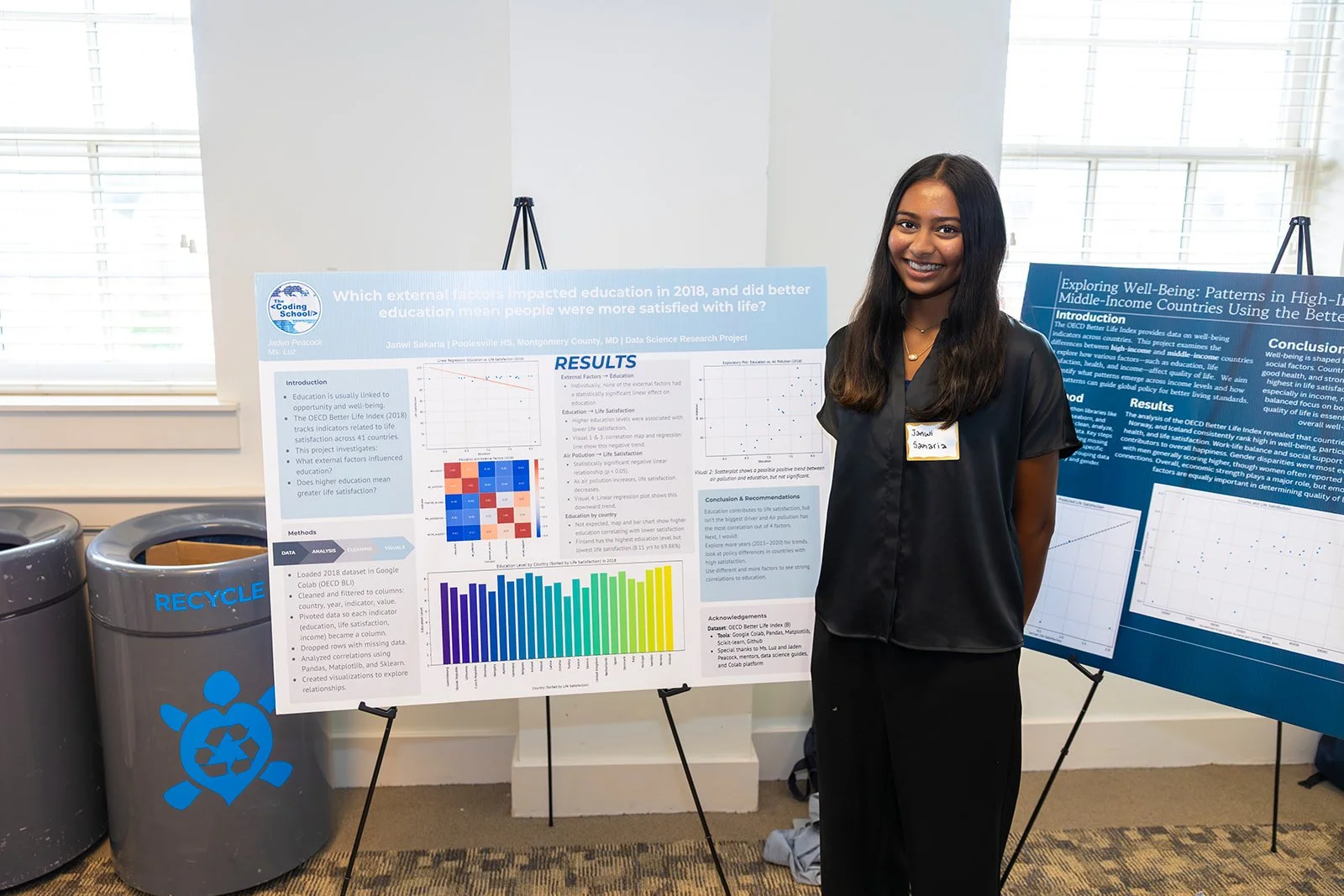 Young woman in black shirt and pants standing next to research poster at an academic conference.