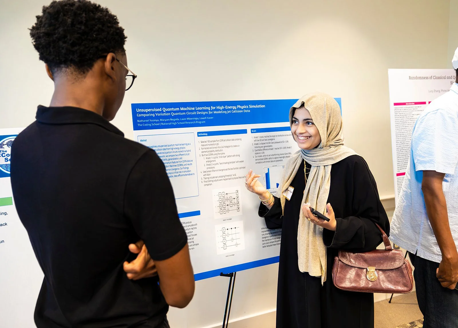 Young woman in hijab explaining a research poster about quantum machine learning to two young men at an academic event.