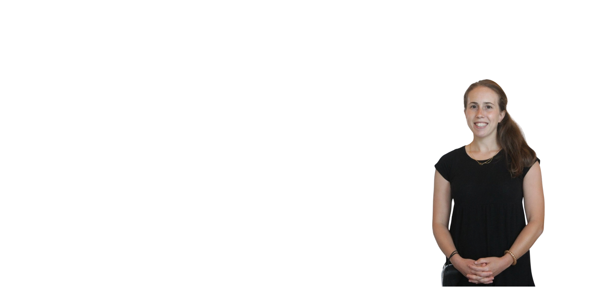 A woman with brown hair, wearing a black dress, smiling and standing with her hands clasped