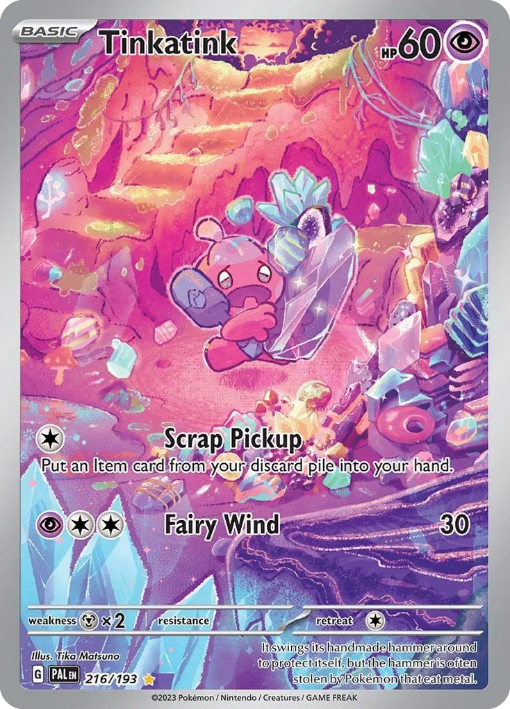 A Pokémon card featuring Tinkatink, a small pink creature with floppy ears, holding a large, sparkling crystal. The background is a colorful, fantasy landscape with crystals and glowing pink formations. The card has a purple and pink color scheme, with Tinkatink's name at the top, and two moves listed: Scrap Pickup and Fairy Wind.