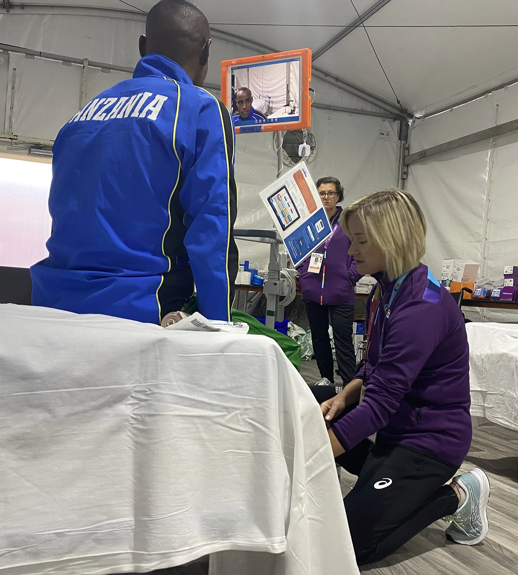 Dr. Erin Wos, woman with blonde hair kneels on the floor, examining a patient.