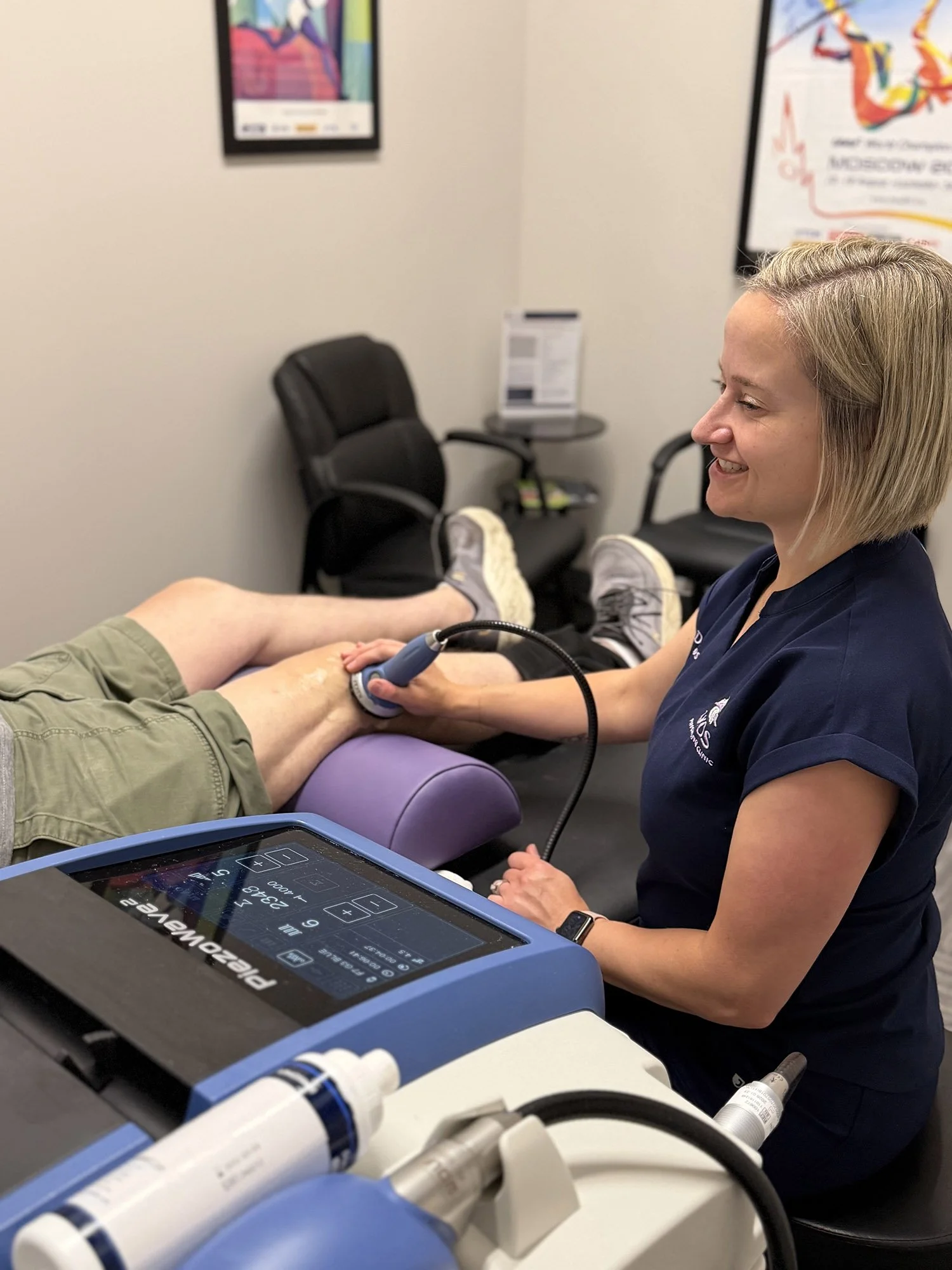 Dr. Erin Wos using ultrasound equipment on a patient's leg in a medical office.