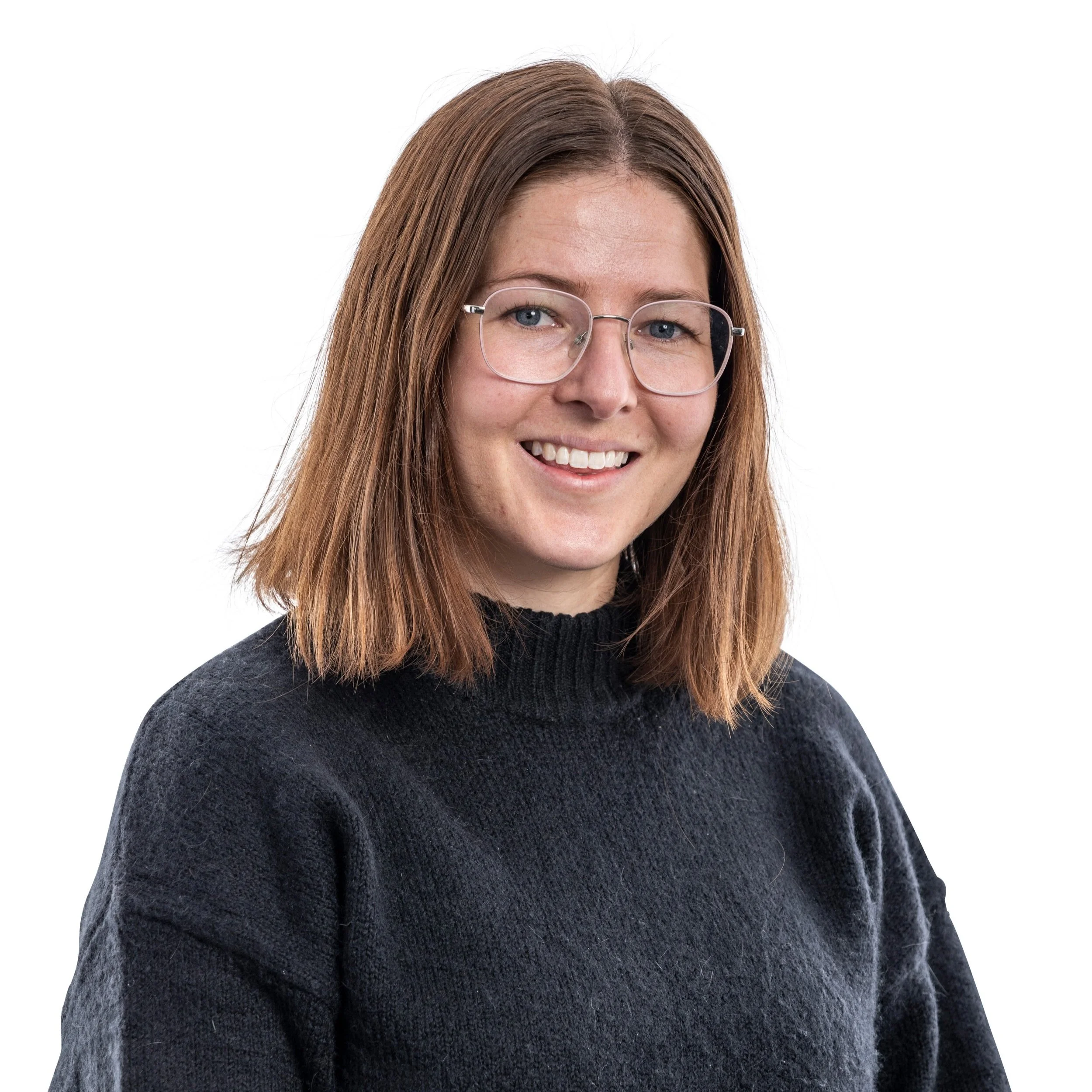 Portrait of a young woman with shoulder-length brown hair, glasses, and a black sweater, smiling against a white background.