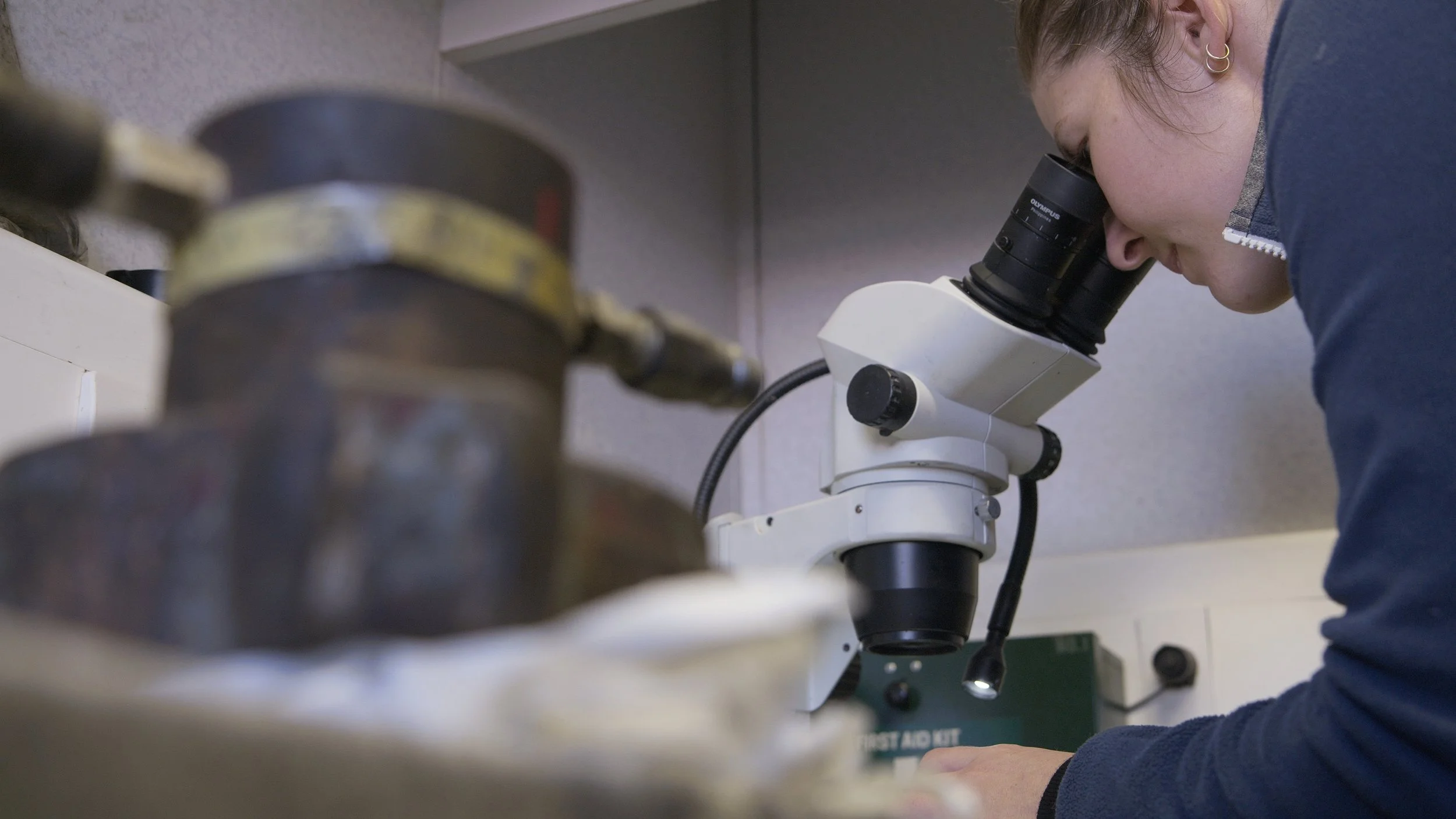 A person using a microscope in a laboratory setting.