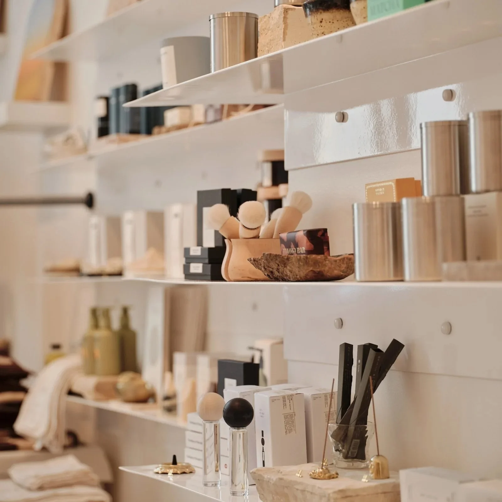 A bunch of white shelves with skincare items and tins on them.