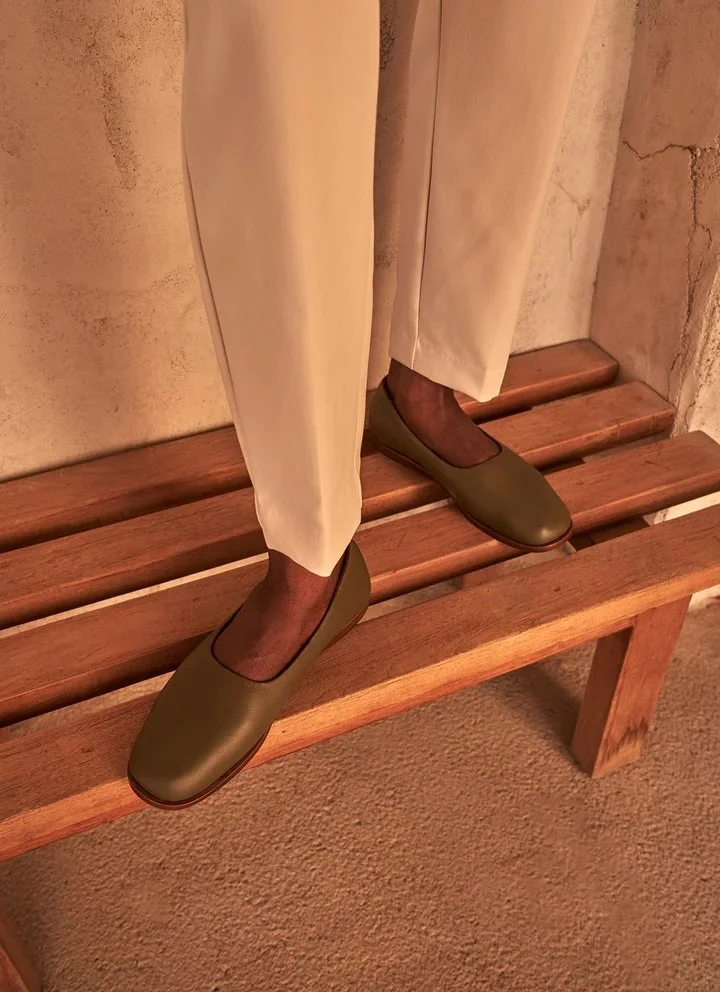 Black woman in tan pants wearing everyday flat shoes in olive from Barkal. Made of Nappa leather.