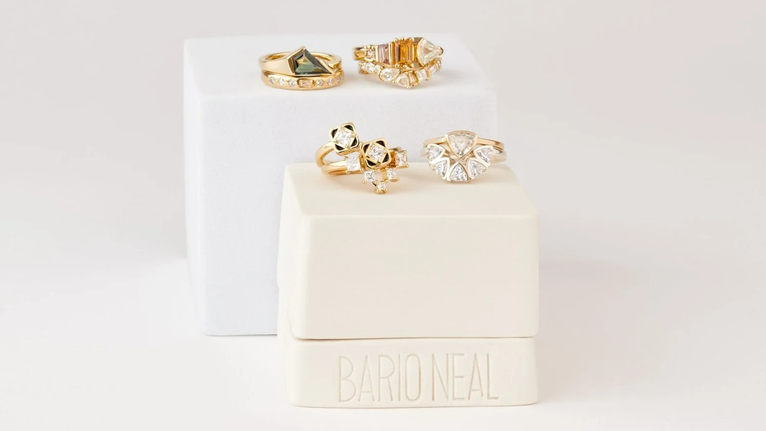 Four gold unique rings from Bario Neal on top of white jewelry boxes.