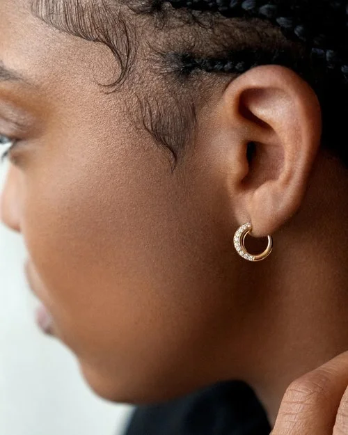 Black woman side profile with a small hoop gold earring aligned with diamonds from Khiry. Braided hair.