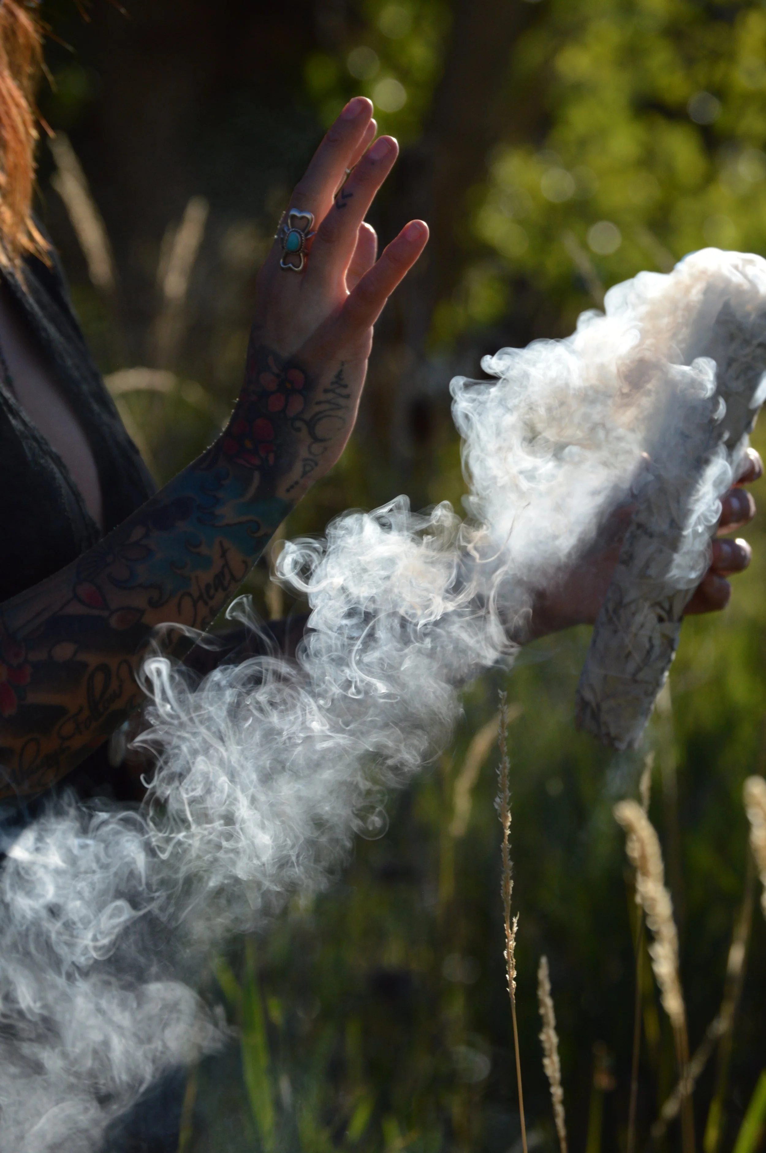 Person holding a large cannabis joint with smoke billowing out, outdoors with green trees in the background.