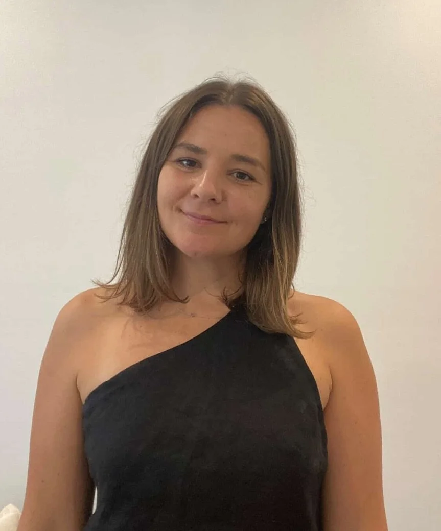 headshot of Roxy. She has long brown hair, she is smiling and wearing a black top.