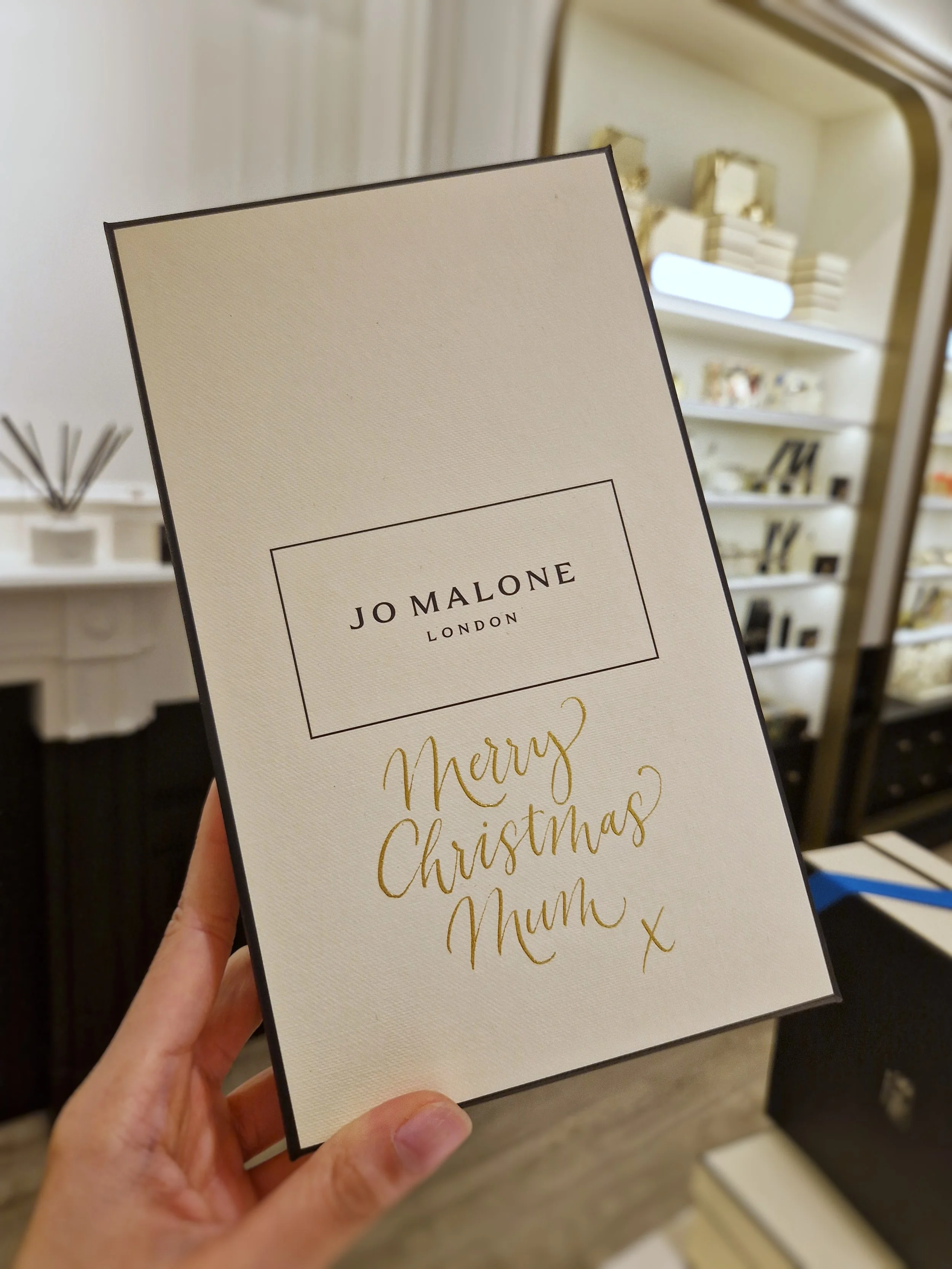 Gold calligraphy on a Jo Malone London gift box saying 'Merry Christmas Mum x'