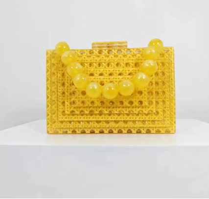 Yellow handbag with round beaded handle made of interconnected small yellow beads, displayed against a plain background.
