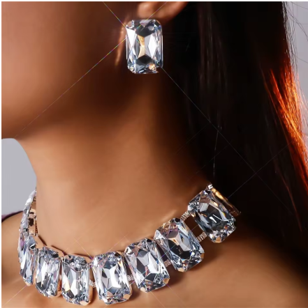 Close-up of a woman wearing a large, rectangular gemstone earring and a matching necklace made of multiple rectangular gemstones.
