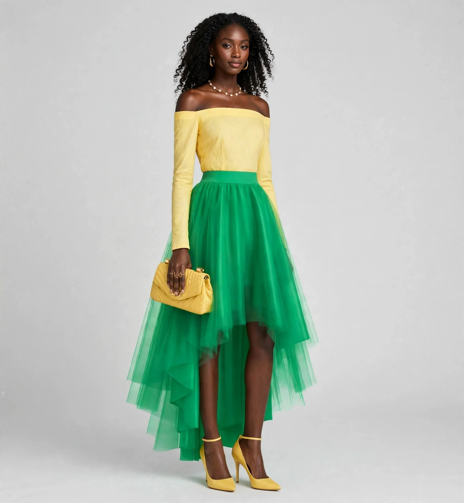 A woman with dark skin and curly black hair standing against a plain gray background, wearing a yellow off-the-shoulder top, a green tulle skirt, yellow high heels, and holding a yellow clutch purse.