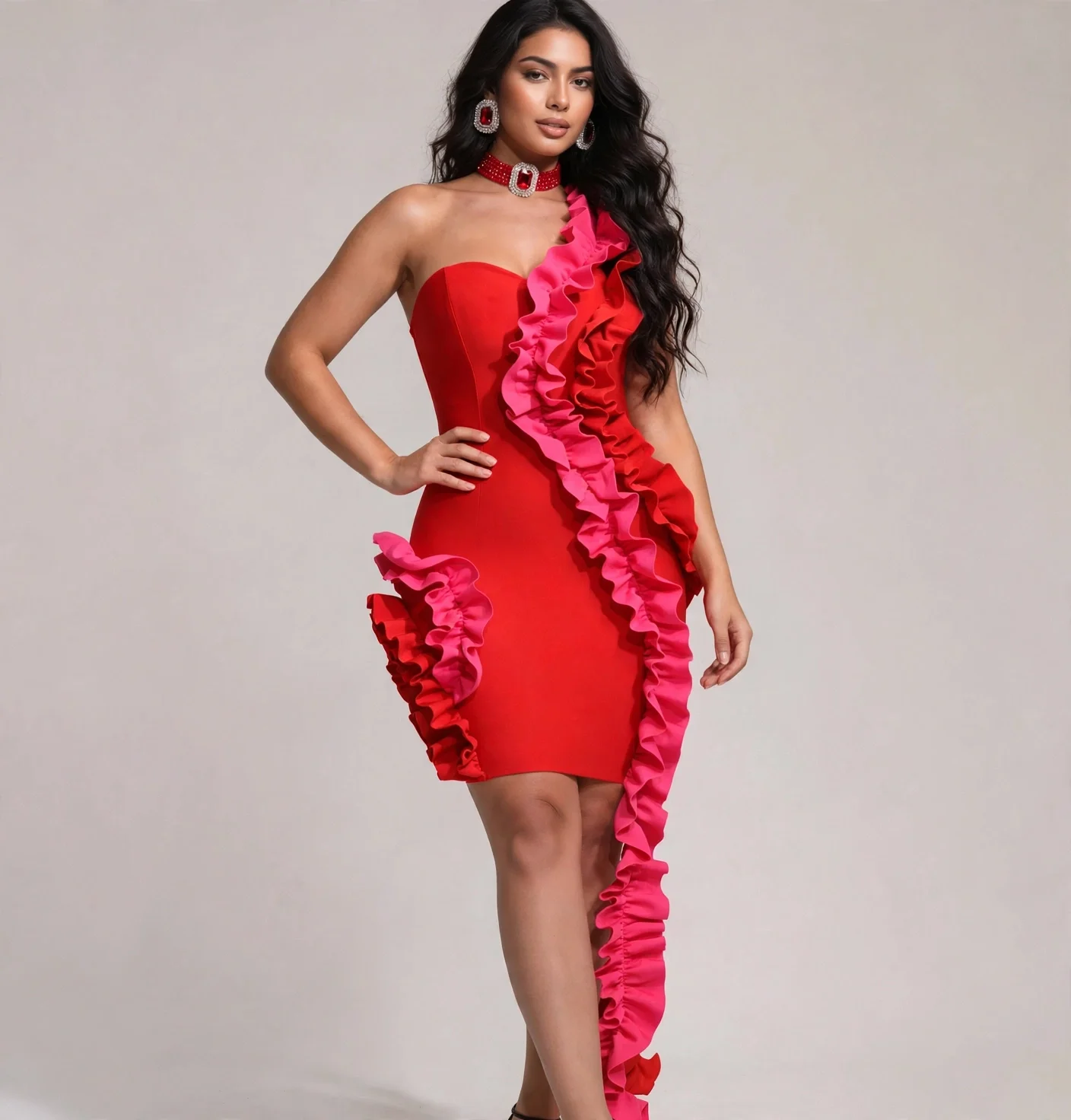 A woman with long dark hair wearing a strapless red dress with pink ruffles and matching jewelry.