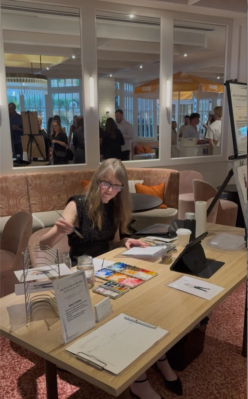 Megan Herbert, smiling and wearing a colorful blouse with floral and abstract patterns, live illustrates a brand activation event VIP customer experience.